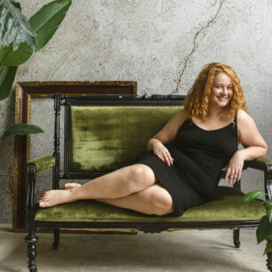 Happy smiling woman sitting in armchair in greenhouse